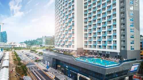 a large building with a swimming pool next to a street at Utop Marina Hotel & Resort in Yeosu