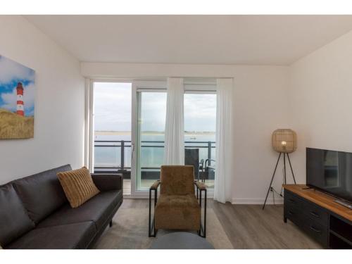 a living room with a couch and a television at Apartment in Sint-Annaland with Water Views in Sint Annaland