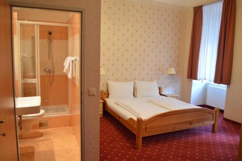 ein Schlafzimmer mit einem Bett und ein Badezimmer mit einer Dusche in der Unterkunft Pension Walzerstadt in Wien