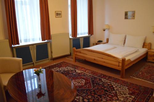 a bedroom with a bed and a table and windows at Pension Walzerstadt in Vienna