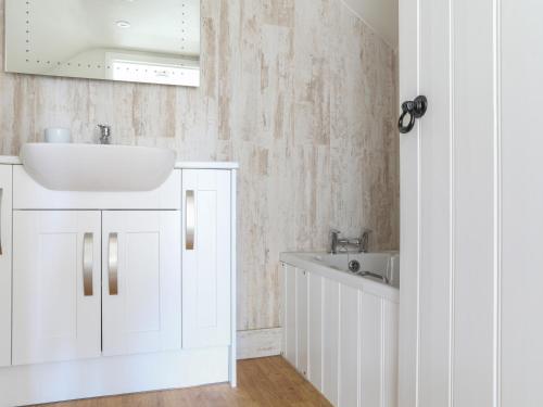ein weißes Badezimmer mit einem Waschbecken und einer Badewanne in der Unterkunft Stable End Cottage in Malborough