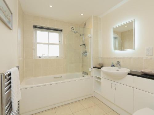 a white bathroom with a tub and a sink at 8 Thurlestone Beach in Thurlestone