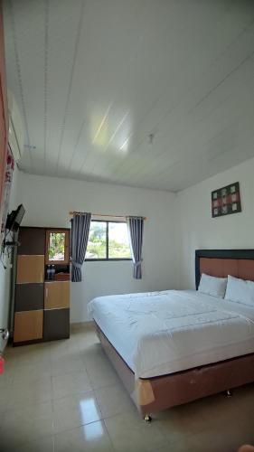 una camera con un grande letto e due finestre di Hotel Sunset Beach labuhan jukung a Krui