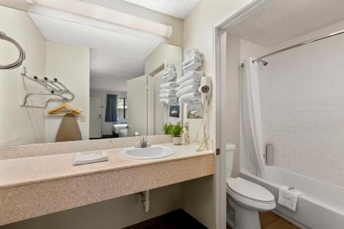 ein Badezimmer mit einem Waschbecken, einem WC und einem Spiegel in der Unterkunft Good Nite Inn Calabasas in Calabasas