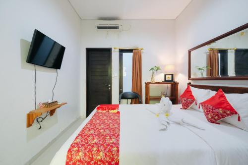 a bedroom with a bed with a tv on the wall at D' Tamblingan Guesthouse Jimbaran Mitra RedDoorz in Jimbaran