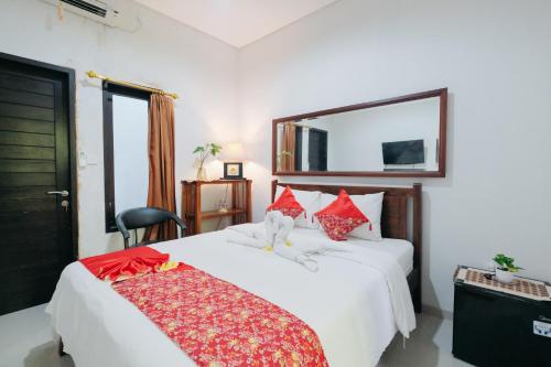 a bedroom with two white beds with red pillows at D'Tamblingan Guest House at Taman Griya Jimbaran RedPartner - Minimum Stay 30 Nights in Jimbaran