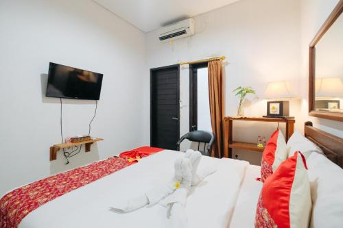 a bedroom with two beds and a tv on the wall at D'Tamblingan Guest House at Taman Griya Jimbaran RedPartner - Minimum Stay 30 Nights in Jimbaran