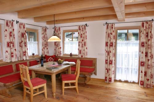 a dining room with a table and chairs and windows at Neuhaushof in Hollersbach im Pinzgau