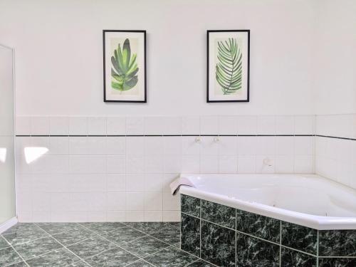 a bathroom with a tub and two framed pictures on the wall at Pea Soup Cottage in Port Fairy