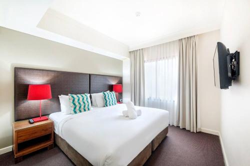 Cette chambre comprend un grand lit et une télévision. dans l'établissement Sunny Seaside Resort Living on The Esplanade, à Darwin