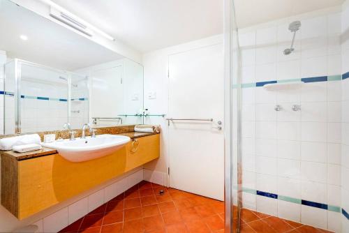 La salle de bains est pourvue d'un lavabo et d'une douche. dans l'établissement Sunny Seaside Resort Living on The Esplanade, à Darwin