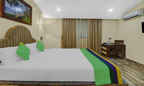 a bedroom with a large white bed and a desk at Treebo Majestic Palms, 2 Km From Colva Beach in Benaulim
