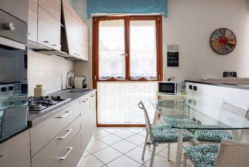 une cuisine avec une table en verre et une fenêtre dans l'établissement Casti - Appartamento MM3 Comasina, à Milan