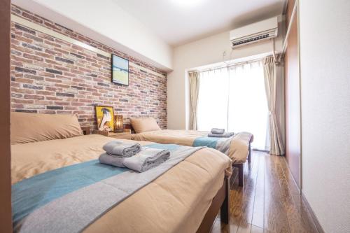 a bedroom with three beds and a brick wall at nestay apartment tokyo akihabara 2A in Tokyo