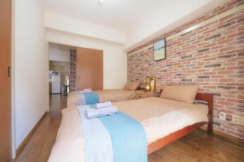 sypialnia z 2 łóżkami i ceglaną ścianą w obiekcie nestay apartment tokyo akihabara 2A w Tokio