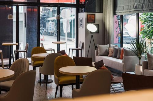 a restaurant with tables and chairs and a couch at OLAH Poshtel - Taichung Station in Taichung