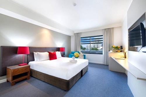 a hotel room with a large bed and a desk at King Studio Harbourfront Haven with Tropical Pool in Darwin