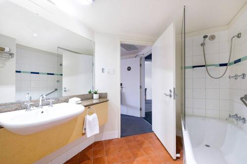 a bathroom with a sink and a tub and a shower at King Studio Harbourfront Haven with Tropical Pool in Darwin