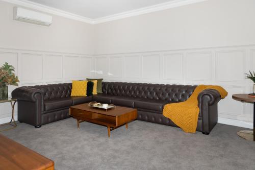 a living room with a leather couch and a coffee table at Mount Gambier Hotel in Mount Gambier