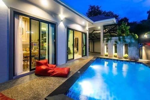 a swimming pool with a red couch next to a house at Nut & Non Pool Villa by Duangtham in Ban Khlong Haeng