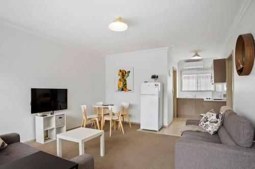 a living room with a couch and a table and a kitchen at Geelong Serviced Apartments in Geelong