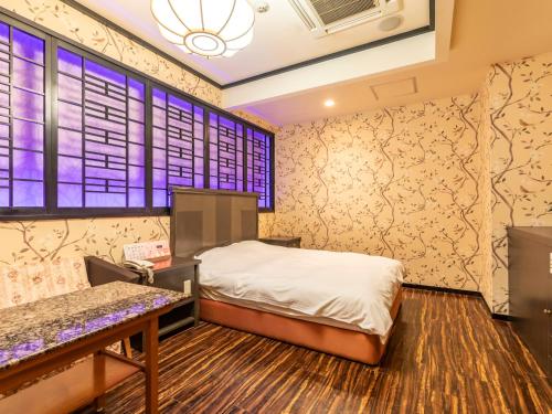 a bedroom with a bed and a window at Tabist Hotel Please Kobe in Kobe