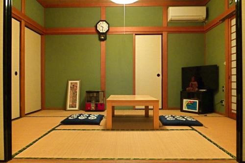 Aoshima Guesthouse Hooju في ميازاكي: غرفة بطاولة وساعة على الحائط