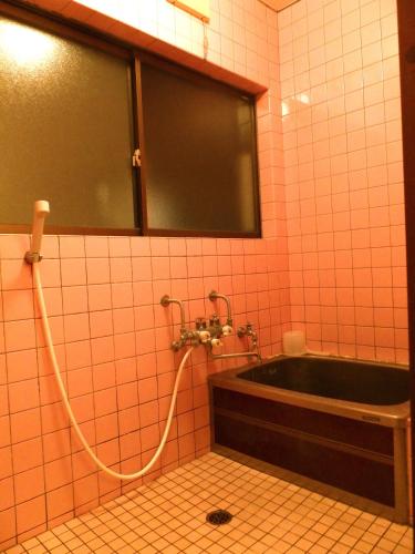 a bathroom with a bath tub and a sink at Aoshima Guesthouse Hooju in Miyazaki