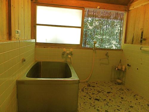 a dirty bathroom with a sink and a window at Kominka Sharehouse Hooju in Miyazaki