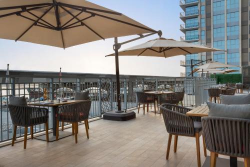 a patio with tables and chairs and umbrellas at Novotel Dubai Gold District in Dubai