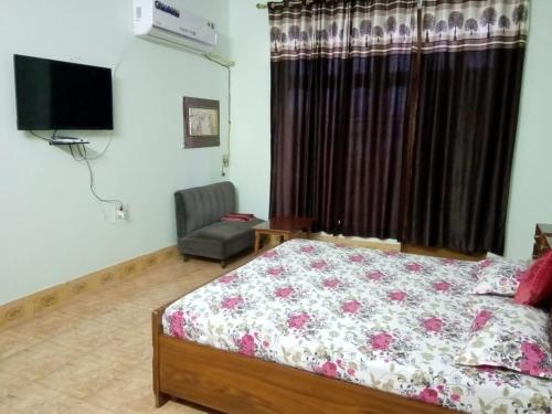 um quarto com uma cama, uma cadeira e uma televisão em KIRAN GUEST HOUSE em Bharatpur