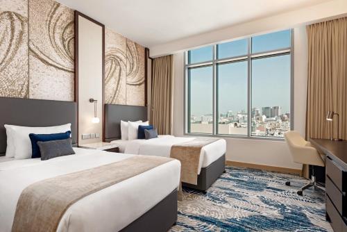 a hotel room with two beds and a window at Novotel Dubai Gold District in Dubai