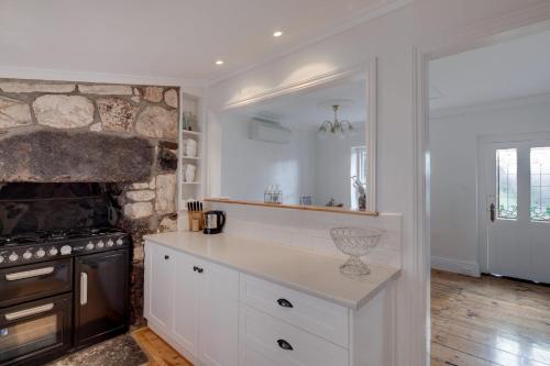 a kitchen with white cabinets and a stone fireplace at Magnetic Cottage circa 1850s in Port Fairy