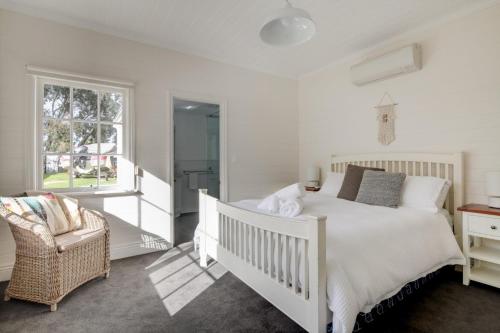 a bedroom with a white bed and a chair at Magnetic Cottage circa 1850s in Port Fairy