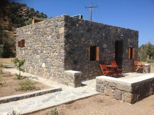a stone building with a table and chairs in front of it at Loutra Olive Garden Stone House #3 in Mandrakion