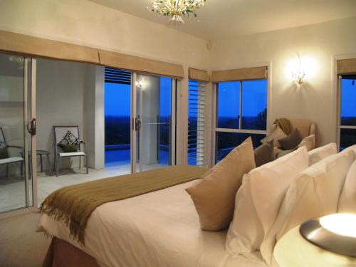 a bedroom with a large white bed with windows at Alexandria Retreat in Doonan
