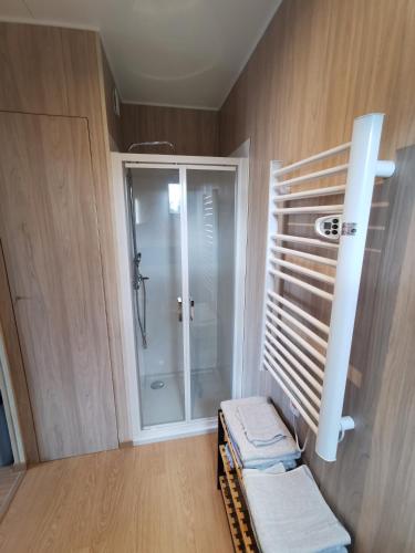 une salle de bain avec une douche avec une porte vitrée dans l'établissement Agréable Tiny house à la campagne, à Coulombs
