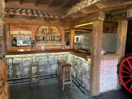 a bar with stools in a room with a stone wall at La Guarida de la Lleira in Ferreras de Arriba