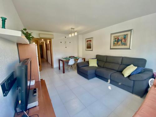 een woonkamer met een blauwe bank en een tv bij Tramuntana apart in Calafell
