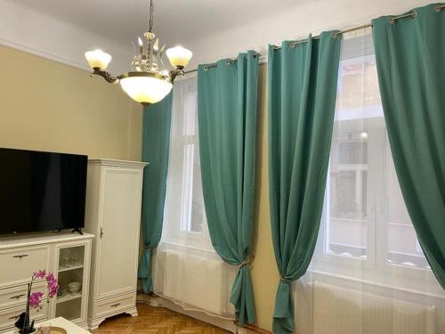 a living room with green curtains and a television at Art Nouveau Apartment Ultracentral in Oradea