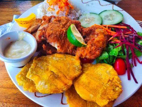 a plate of food with chicken and rice and vegetables at Poetry Garden Bocas Town Colon Island- Deluxe Bungalow Cabin-AC-Enjoy the Night Life in Bocas del Toro