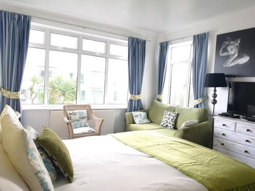 a bedroom with a bed and a chair and window at Blue Palms in Bournemouth