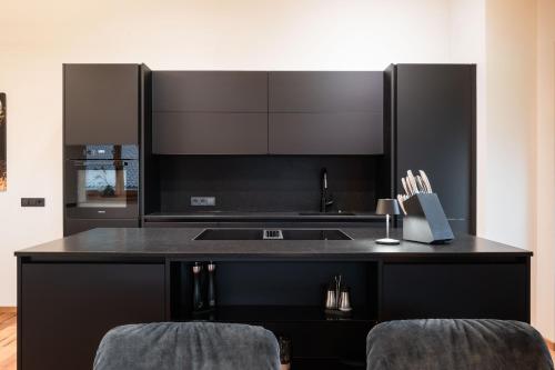 a black kitchen with a sink and a counter at Hohe Tauern Lofts Panoramabahn by Alpina-Holiday in Dorf