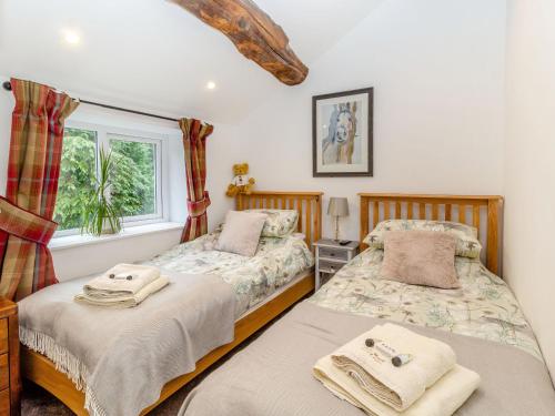 a bedroom with two beds and a window at Fox Bank Cottage in Macclesfield