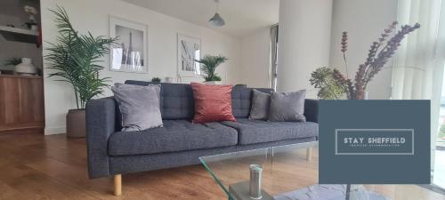 a blue couch with pillows in a living room at City Centre 2 Bedroomed Apartment - Great views - wifi in Sheffield