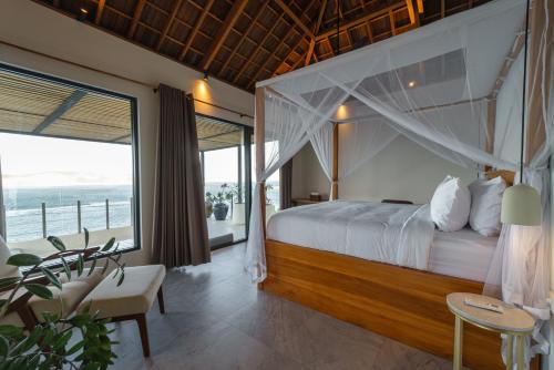 a bedroom with a bed with a view of the ocean at Villa Utamaro in Bumbang
