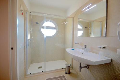 La salle de bains est pourvue d'une douche, d'un lavabo et d'un miroir. dans l'établissement Hotel Residence Il Gabbiano, à Cirò Marina