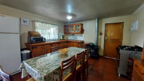 a kitchen with a table with chairs and a counter top at Apple Blossom Cottage in Dullstroom