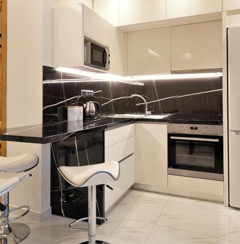a kitchen with white cabinets and black appliances at Estilo luxury apartment in Kavala