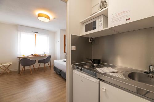 a kitchen with a sink and a room with a bed at Cerise Nantes La Beaujoire in Nantes